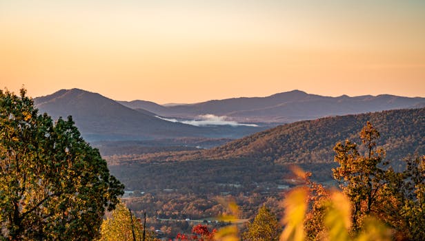 A stunning landscape of mountains during a colorful autumn sunrise, offering a serene view.