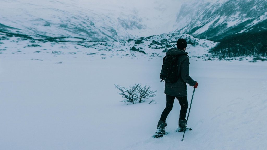 A person hikes through snow-covered mountains in winter, showcasing solitude and adventure.