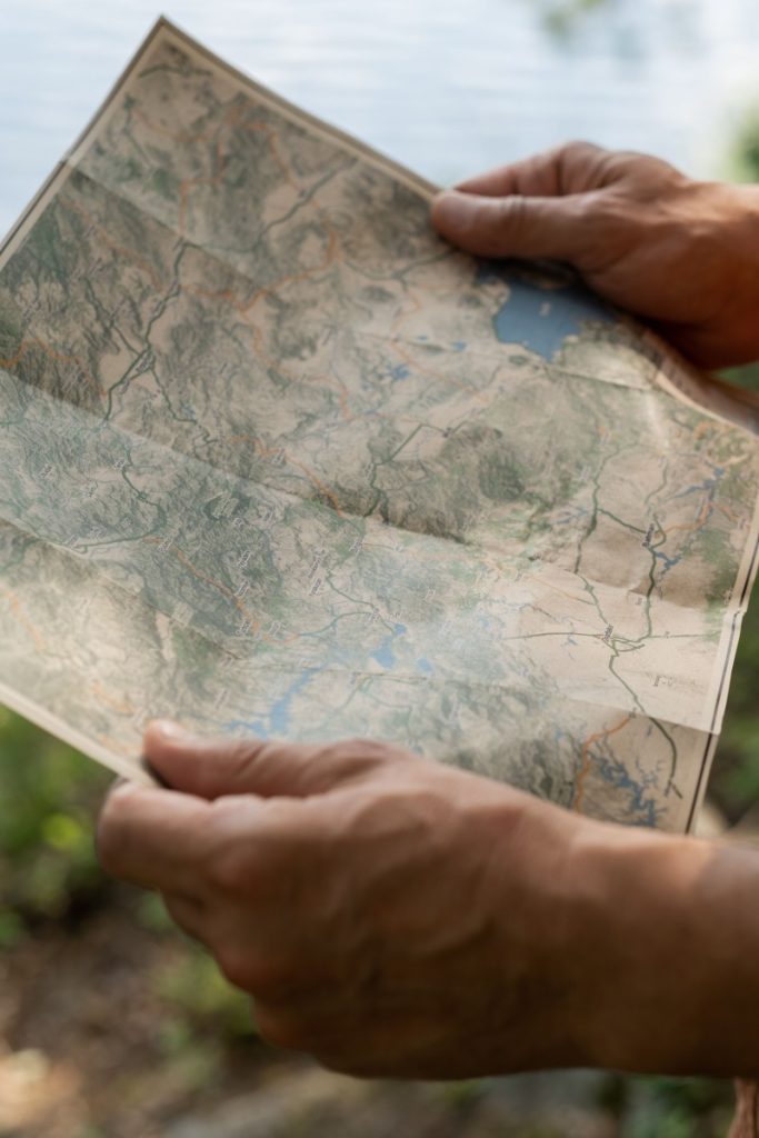 Close-up of a person holding a map while hiking outdoors, emphasizing navigation and exploration.