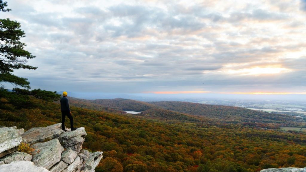 Man on standing on rock overlook with view of landscape below