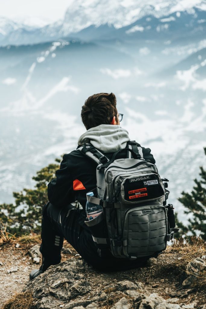 A person enjoys a scenic view from a snowy mountain while wearing a backpack.