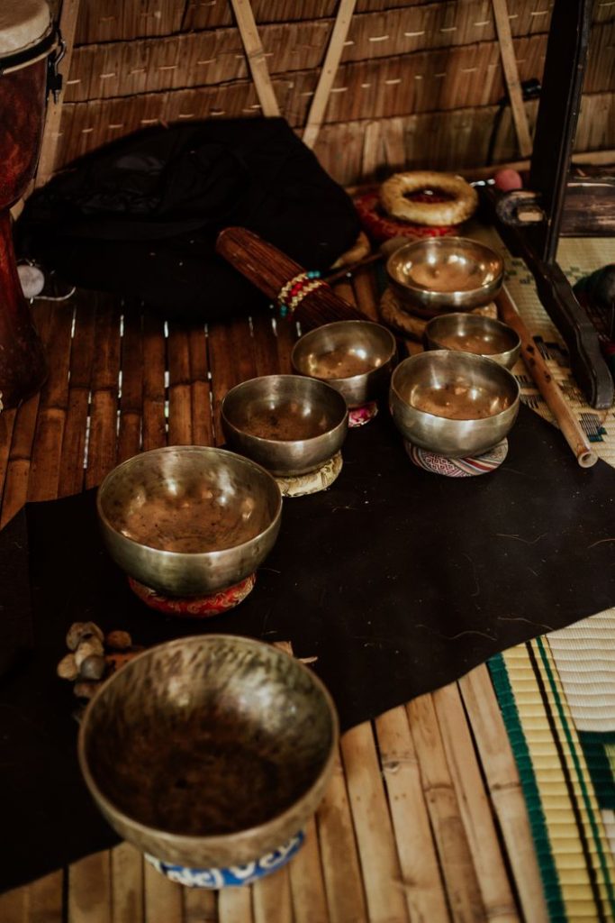 A collection of Tibetan singing bowls arranged on a bamboo mat in an indoor setting.