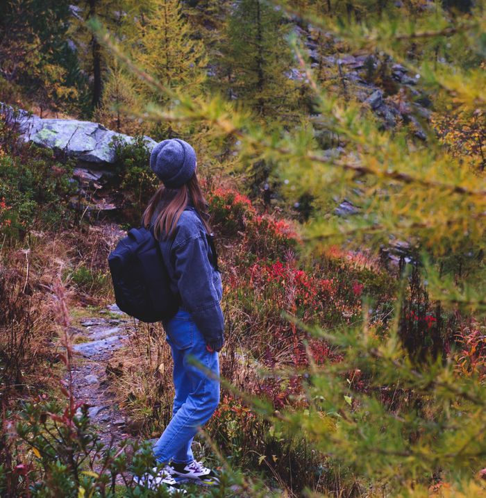Young woman hiking through a colorful autumn trail with a backpack.