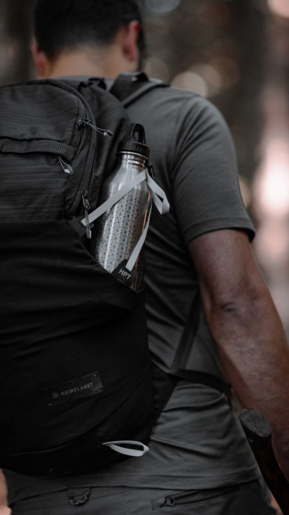 Back view of a man hiking in İstanbul, carrying a backpack with a bottle. Adventure spirit.