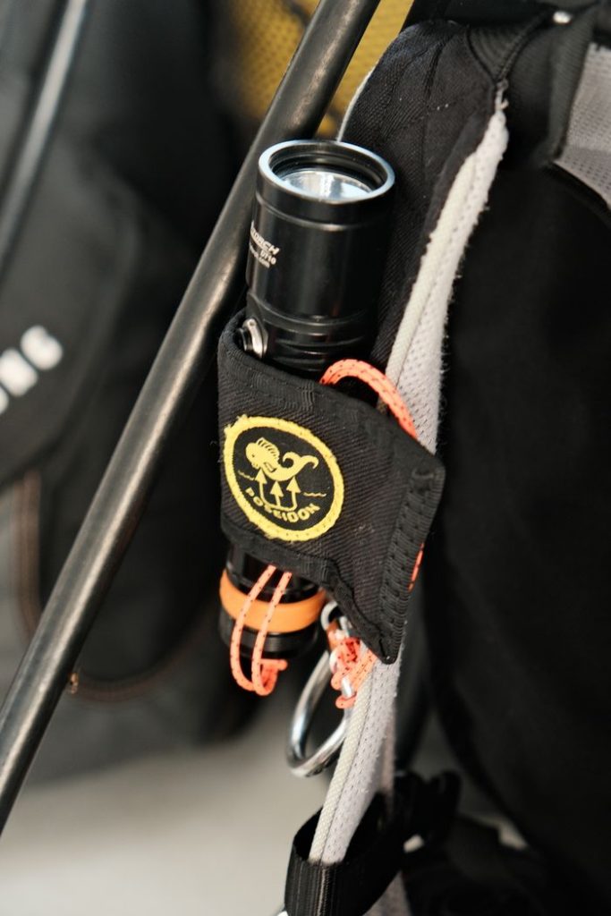 Close-up of a flashlight mounted on a trekking backpack, perfect for outdoor adventures.