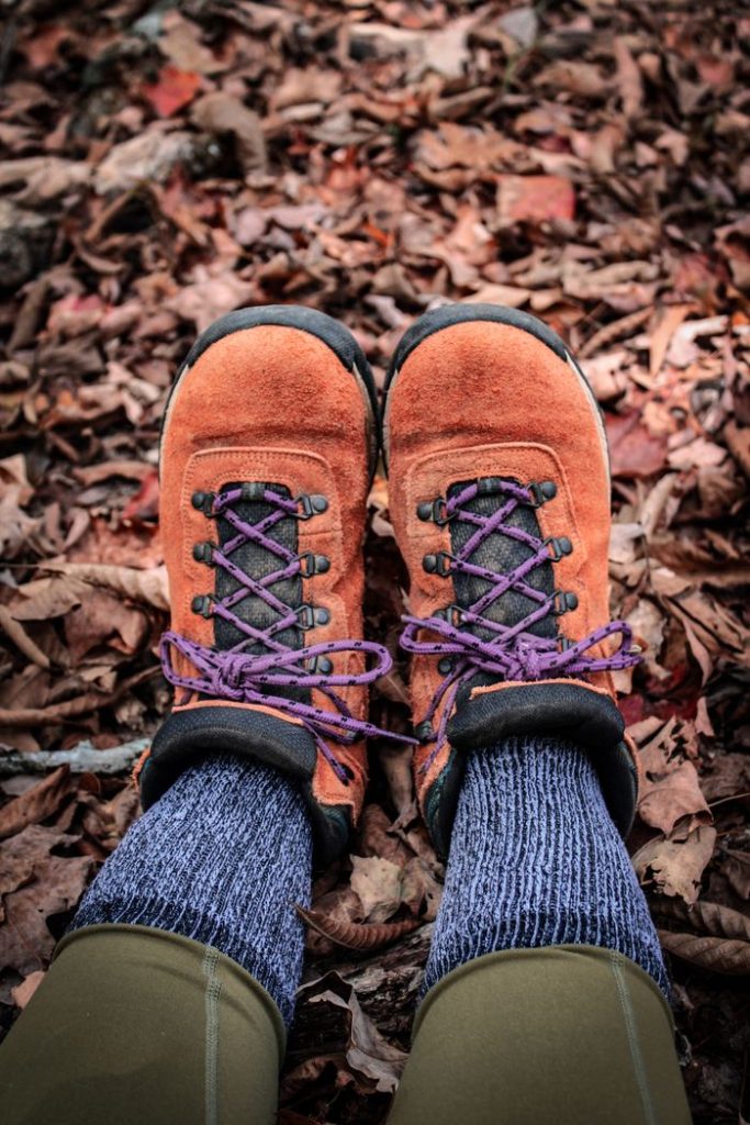 Close-up of hiking boots on fallen leaves, perfect for fall adventures.