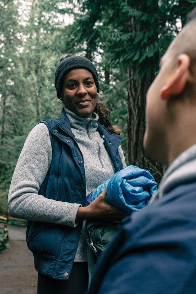 Two adults chatting and enjoying a forest hike, embracing outdoor lifestyle.
